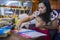 Young student doing homework at home with school books, newspaper and digital pad helped by his mother. Mum writing on the