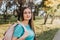 Young student girl, carrying a backpack and looking at the camera with a serene smile in a park road. Future path