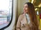 Young student girl looking through the window sitting in the tram