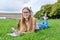 Young student girl lying on grass, educational building background