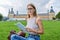 Young student girl sitting on grass, educational building background