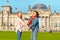 Young student girls having fun and dancing and piggybacking on the grass near famous landmark in Berlin - Bundestag building.