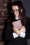 Young student in glasses with books in hand, mysteriously looking at the camera