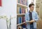 Young student with glasses in library looking to his left side and holding a book in his hands