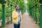 Young student male with beard having stylish clothes standing against green background using mobile phone for downloading video. B