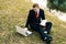 Young student is studying on the nature in the park near the lake. a guy in a black suit and red tie reads a laptop and