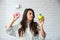 Young student woman doubts what to choose healthy food or sweets junk unhealthy food holding green apple and donut in hands