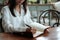 Young student woman sitting at library holding pen and writing o