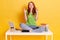 Young student woman in workplace with laptop and books, sitting with fingers crossing, wishes best, sitting with crossed legs on