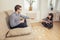 Young students doing homework while sitting on sofa and woman sitting on floor