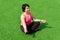 Young sturdy chubby woman meditates on the lawn after exercising