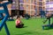Young sturdy chubby woman meditates on the lawn after exercising in the courtyard of a city house against the background of street