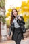 Young stylish Asian woman walking in city street, autumn lifestyle wearing fashion black leather jacket. Vertical