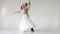 Young and stylish ballet couple dancing on white background