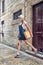 Young stylish blonde with hat and summer dress on a walk. Old buildings, European city. Summer holiday. Lifestyle, fashion,