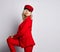 Young stylish blonde woman is posing in elegant deep red official suit, red cap and massive earings looks back