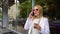 Young stylish blonde woman talking on phone holding coffee cup on the street