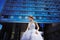 Young stylish bride on blue glass office building background