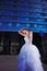 Young stylish bride on blue glass office building background