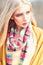 Young stylish girl with straight blond hair wearing stripped multicolored scarf, yellow jumper and cardigan posing