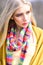 Young stylish girl with straight blond hair wearing stripped multicolored scarf, yellow jumper and cardigan posing