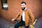 Young stylish man with a beard sitting on bicycle on a brick background