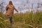 Young stylish man in beige jacket and jeans runs in nature jubilee dried autumn colors. Cloudy weather, dry grass