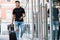 Young stylish man with black T-shirt and ripped jeans carrying a luggage