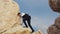 Young stylish man walking on the rock outdoors. Successful free guy standing on a big stone. Cyprus. Paphos