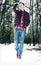 A young stylish man walking through snowy forest