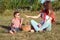 Young stylish mother having fun with her little son on the picnic in the open air. Boy is blowing soap bubbles and laughing