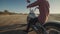 Young stylish motorcyclist sitting on his motorbike in the desert road during sunset