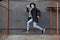 Young stylish redhead man in trendy outfit have fun and jumping against urban wall outdoors.