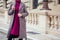 Young stylish woman buttoning coat buttons walking on the street in Czech Republic Prague sity