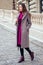 Young stylish woman buttoning coat buttons walking on the street in Czech Republic Prague sity