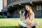 Young stylish woman doing peace sign, relax with coffee and sitting on green grass