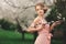 Young stylish woman near blossoming flowering tree in the park. spring background. blonde girl with hairstyle in pink dress. copy