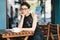 Young stylish woman with stylish glasses sitting at table in cafe with a big cup of coffee or latte