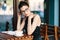 Young stylish woman with stylish glasses sitting at table in cafe with a big cup of coffee or latte