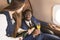 Young successful Afro-American businessman in glasses and a stewardess shows a bottle of wine in the cabin of a private