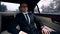 Young successful businessman going to meeting in luxury auto, traffic in city