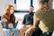 Young successful coworkers sitting on chairs in circle, discussing working or personal issues together.