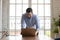 Young successful male manager leaning over table writing email.