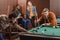 young successful multiethnic friends playing in pool