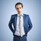 Young successfull businessman in suit and grey tie on blue background, close up