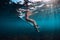 Young surf girl at surfboard underwater in sea