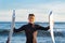 Young surfer comes out of the water carrying the broken board in the middle. Handsome guy with wetsuit. Horizon over the water