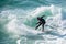 Young surfer enjoys the waves confronting the surf by surfing the rougher waters after a morning rain storm