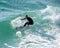 Young surfer enjoys the waves confronting the surf by surfing the rougher waters after a morning rain storm