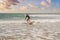 Young surfer learning to surf in black wetsuit, sunny day on ocean beach